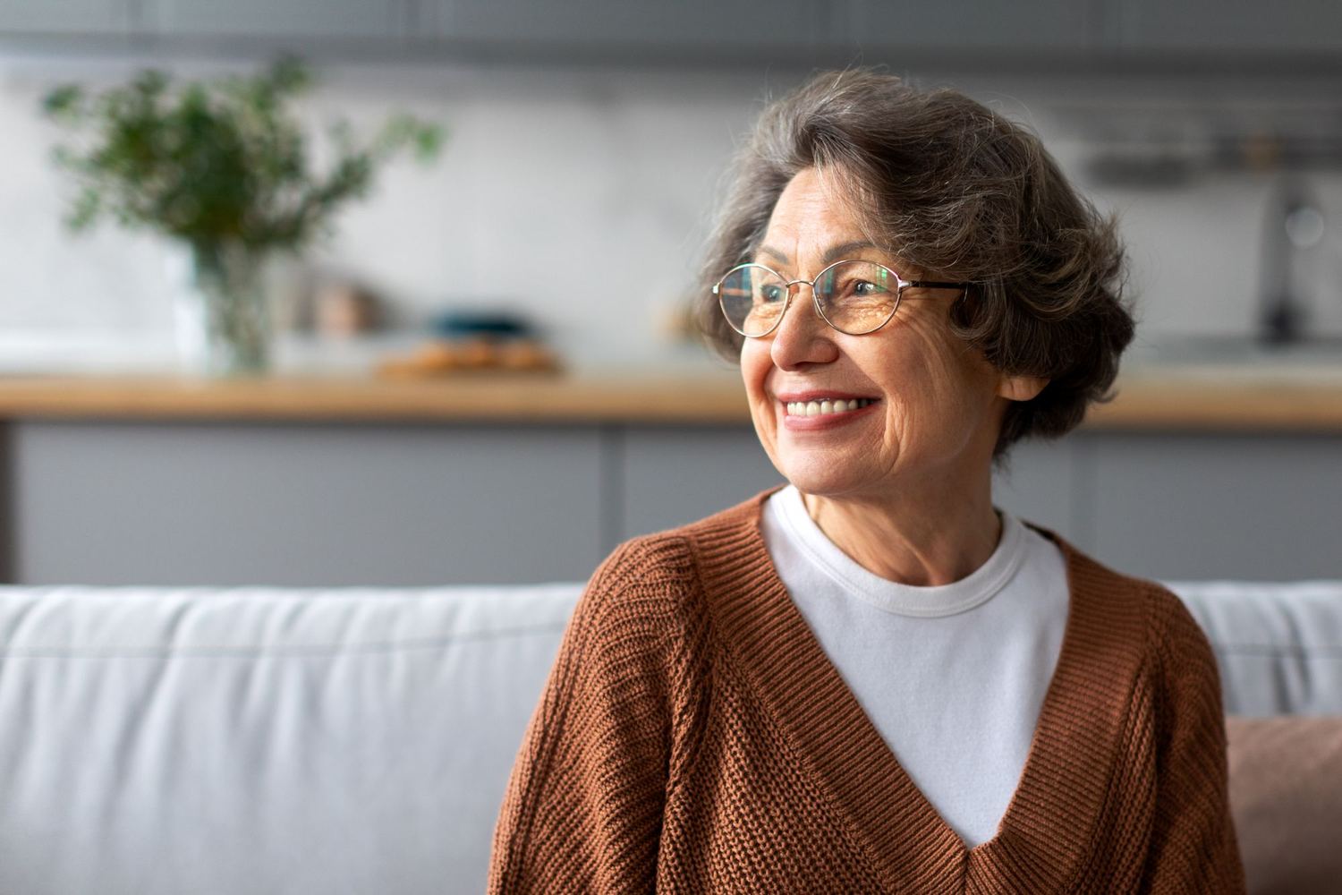 A smiling woman in her sixties at home in her kitchen.