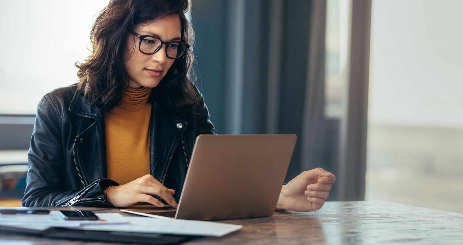 A woman reviewing something on her laptop at a table.