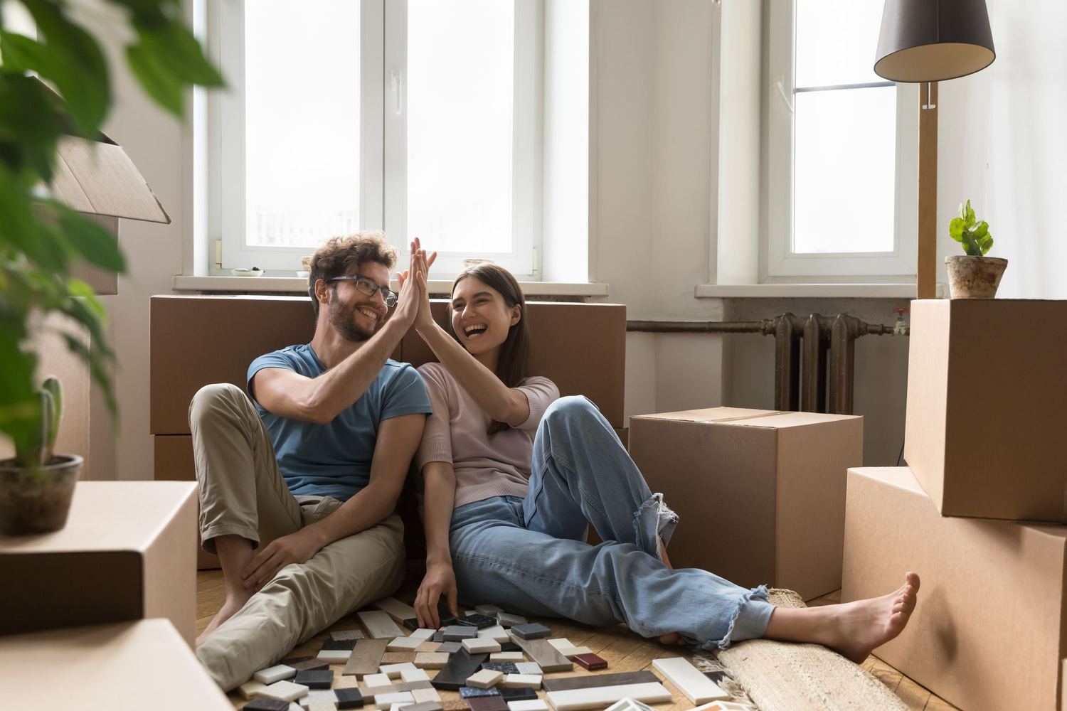 A young couple sitting on the floor among moving boxes.