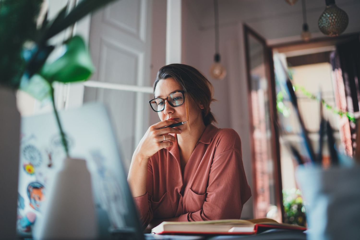 A woman at her desk resting her chin on her hand, thinking.
