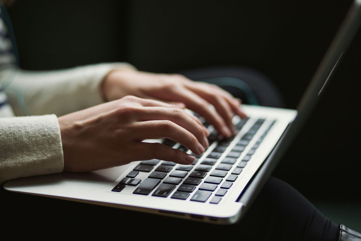 Hands typing on an open laptop.