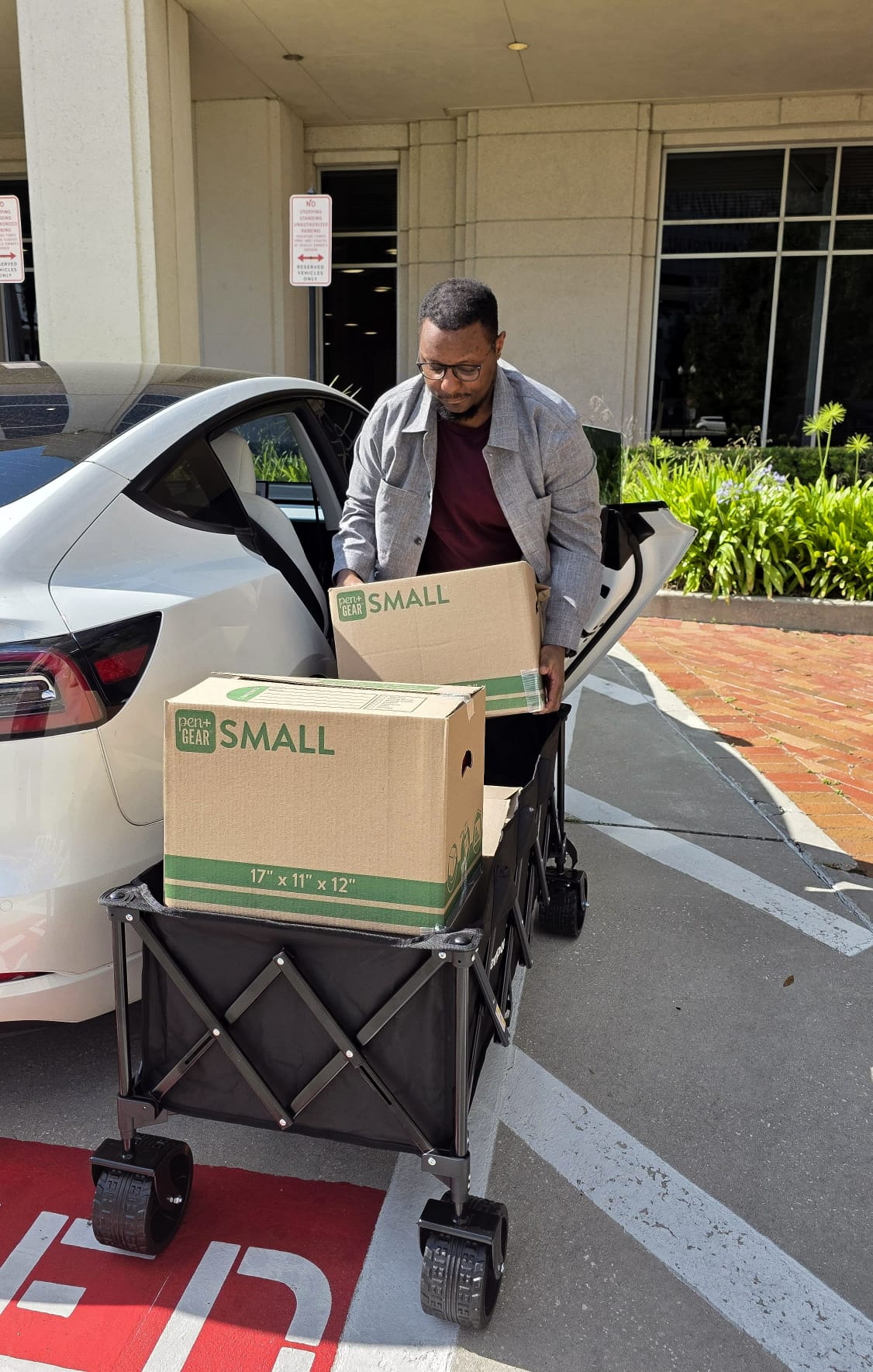 Derrick Johnson unloading boxes of school supplies from a car into a wagon