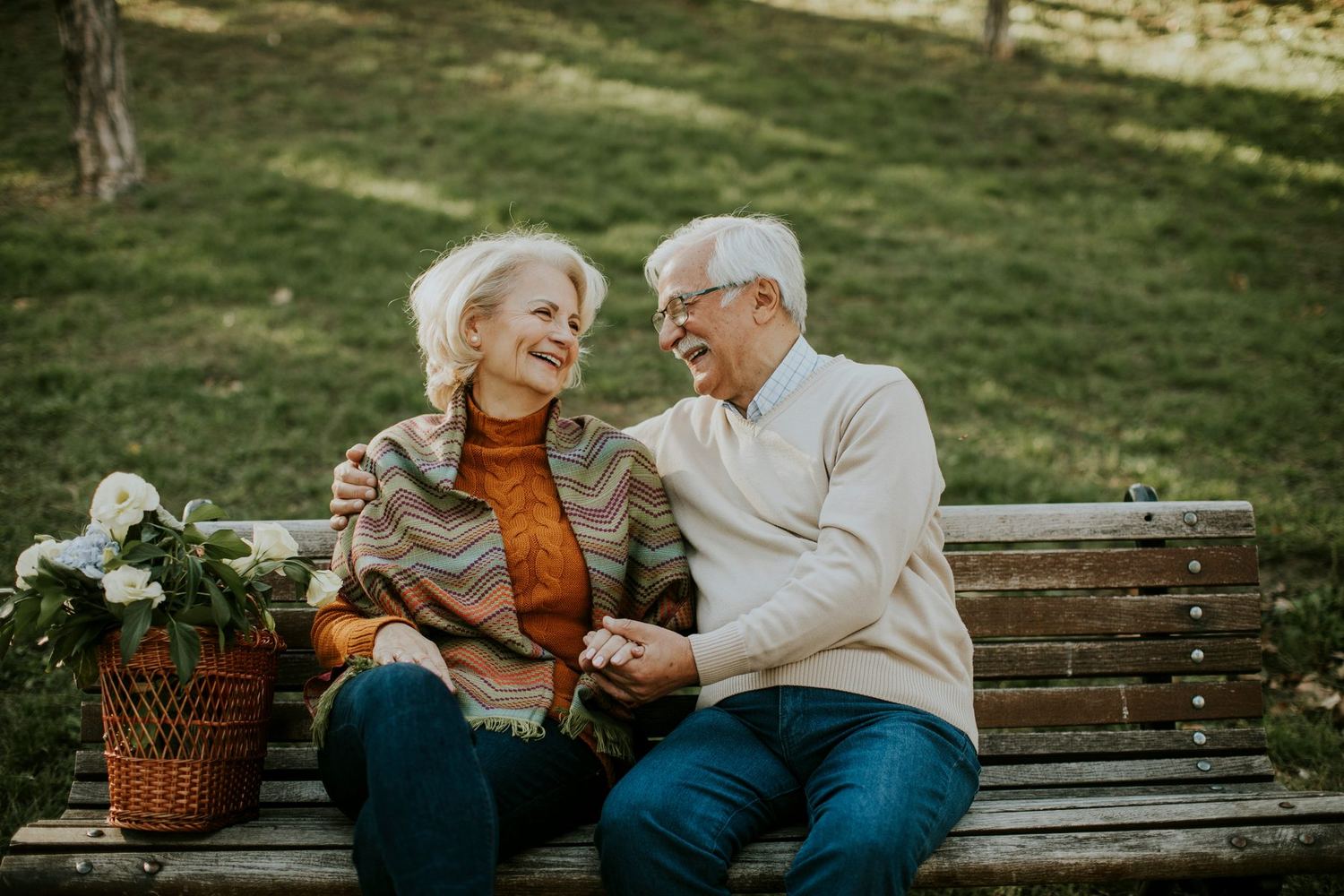 An older couple sitting together on a park bench