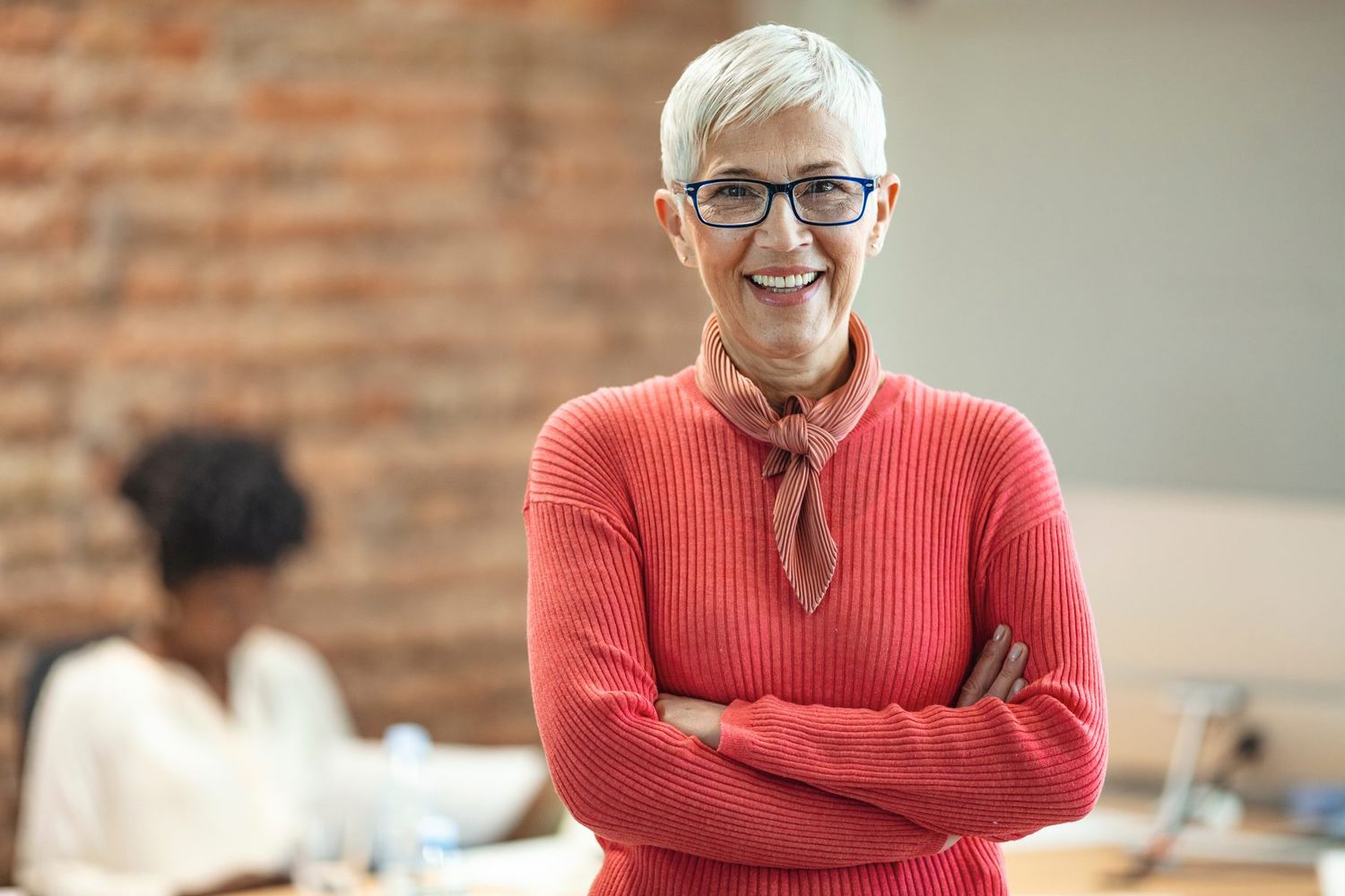 A woman in a red sweater smiling in an office